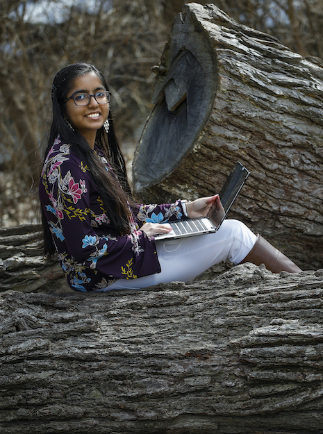 Arpita Kumari, UIC '21, sits with her laptop in a natural outdoor park setting