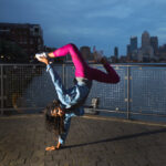 A breakdancer in hot-pink pants and a blue shirt performs in an urban park