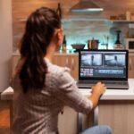 A female video editor processes footage on her laptop