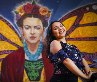 Cecilia Avila, UIC '20, in front of a professionally painted mural in Chicago