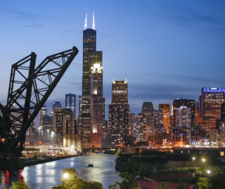 The Chicago skyline at night with an open rail bridge in the foreground