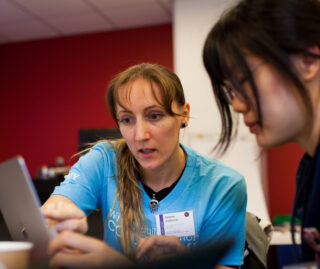 A representative of a Break Through Tech partner company works with a student participant at a laptop