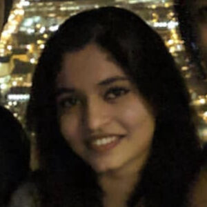 headshot of Diya with the nighttime lights of Chicago in the background
