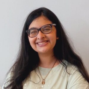 headshot of Drishika wearing a pale-green sweatshirt and gold necklace