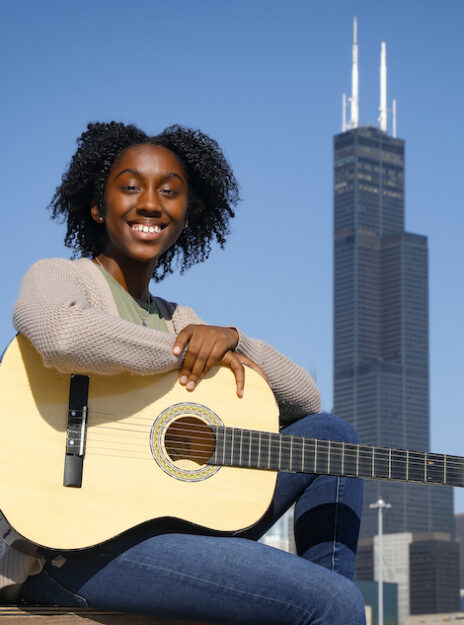 Charlotte Andry, a very music-oriented UIC computer science student, poses with her guitar with the Sears Tower in the background